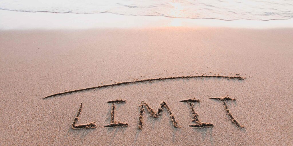 le mot "limit" écrit sur la sable avec la mer au bord